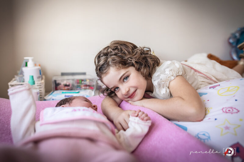 sesión newborn a domicilio y foto de una hermana mayor en el cambiador de su habitación